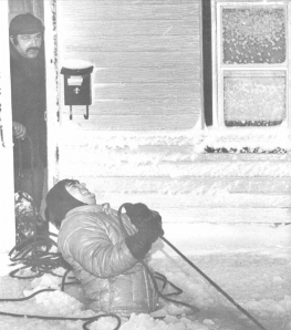 Rescue worker struggles to haul evacuation boat to the front door of this home in Revere, Mass (photograph by Paul Benoit, Boston Herald American).